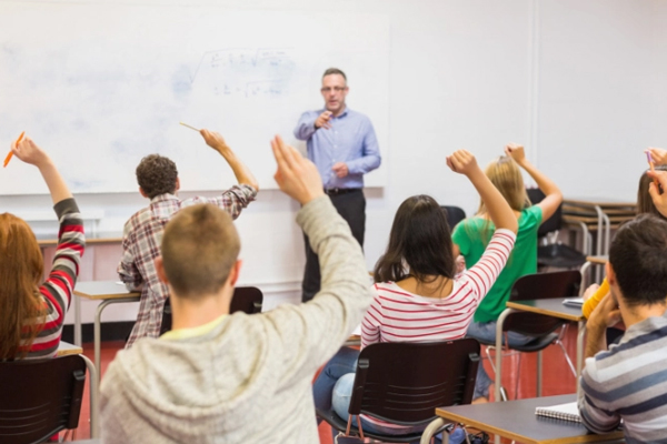 Students raising hands as teacher tries to choose