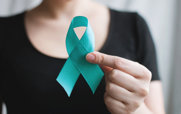 Girl in black shirt holding a teal ribbon