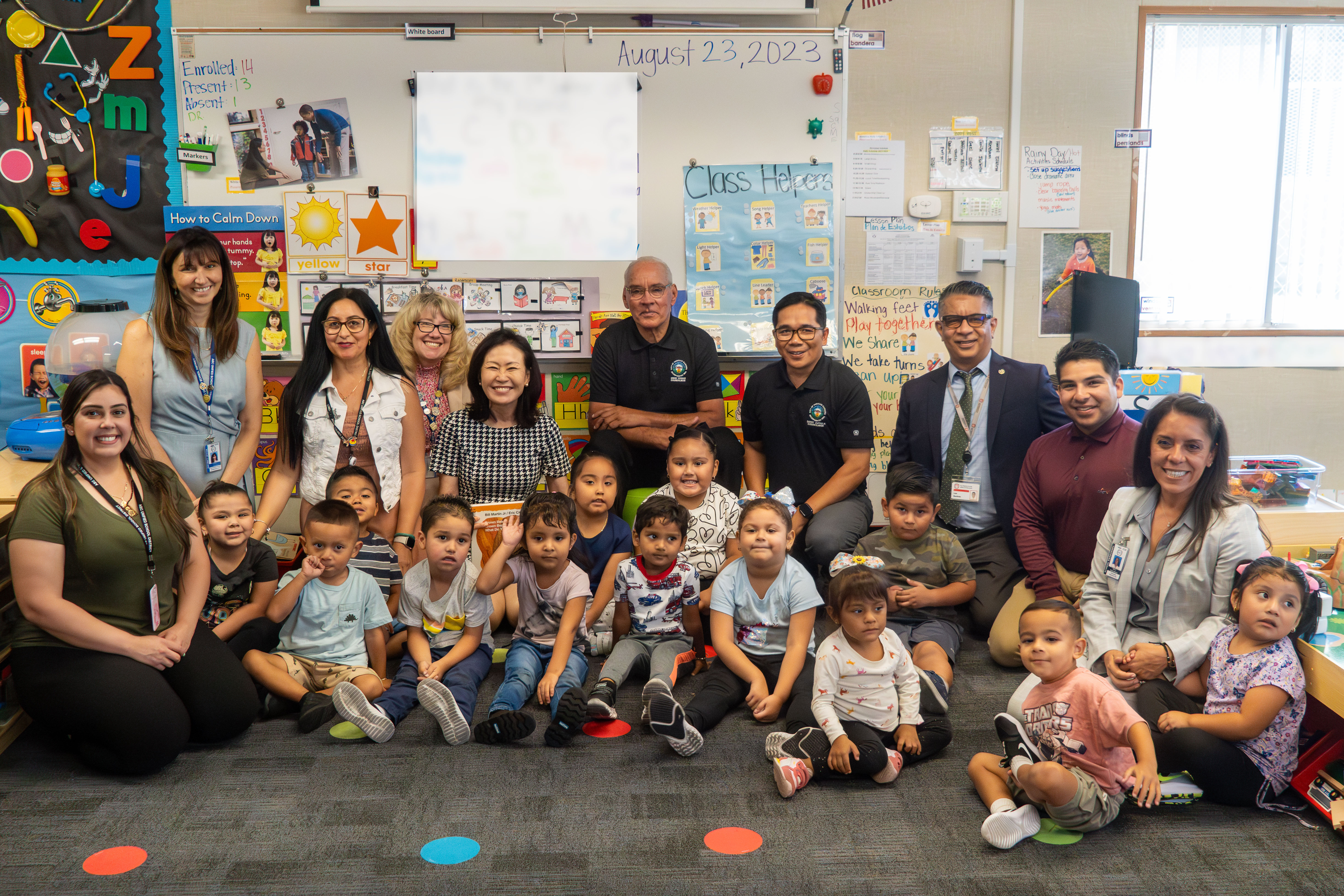 Congresswoman Steels sits in the middle of students and teachers and smile for photo