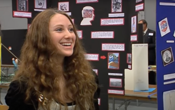 High school student standing in front of History Day LA poster presentation