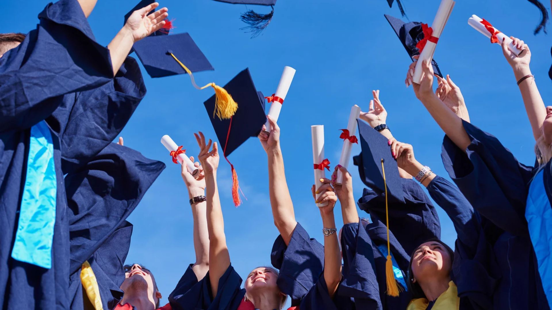 Students celebrate by throwing their graduation cap in the air