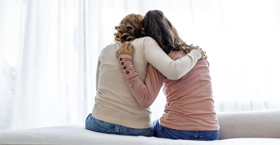 Two women put their arms around each other.