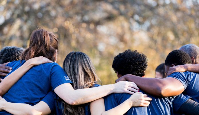 A group putting their hands on shoulders