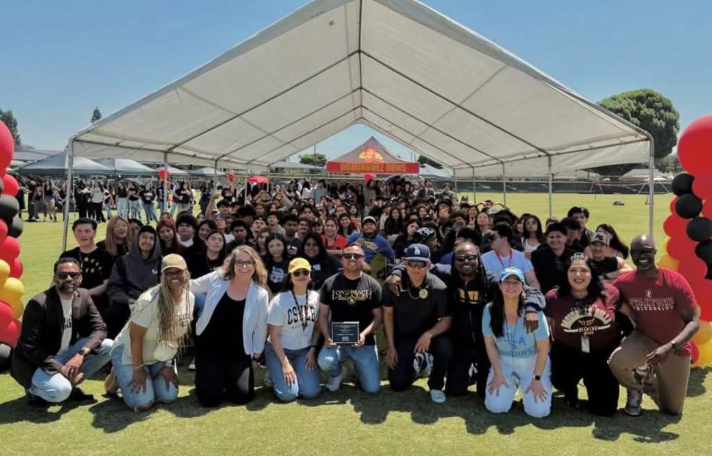 Students, teachers and counselors posing for a group photo under a white tent