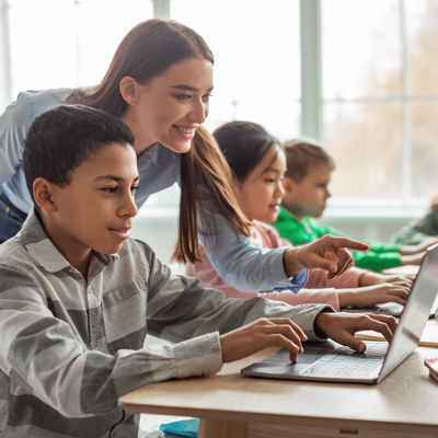 Teacher helping a student on a laptop