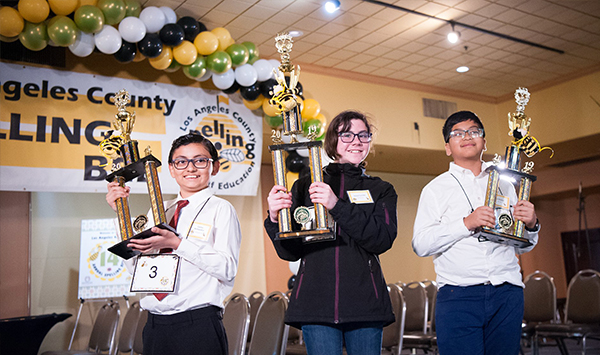 Students holding up Spelling Bee trophies