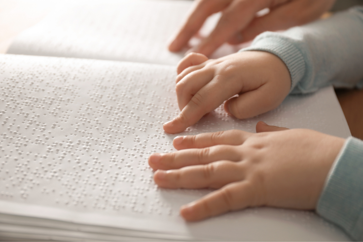 Child reading braille with an adult