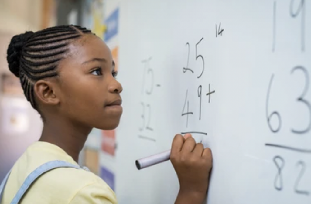Girl doing math problems on classroom white board