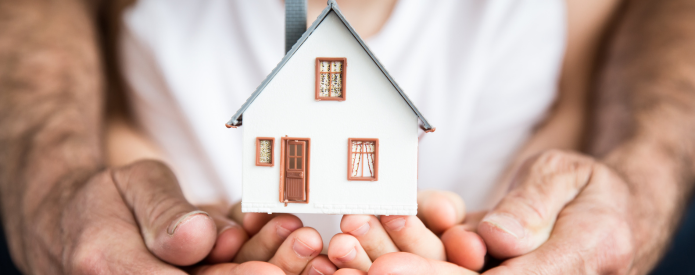 Picture of father and daughter's arms holding a house