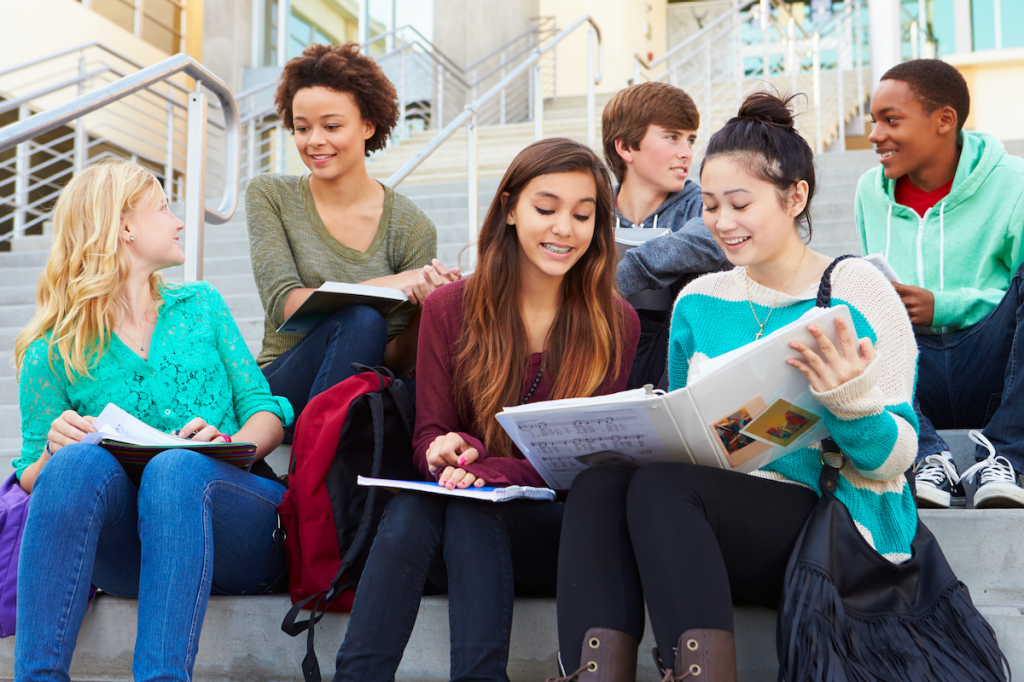 Group of high school students talking and sharing notes