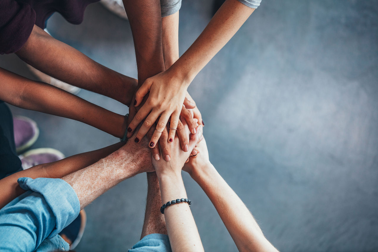 Close up top view of young people putting their hands together. Friends with stack of hands showing unity and teamwork.