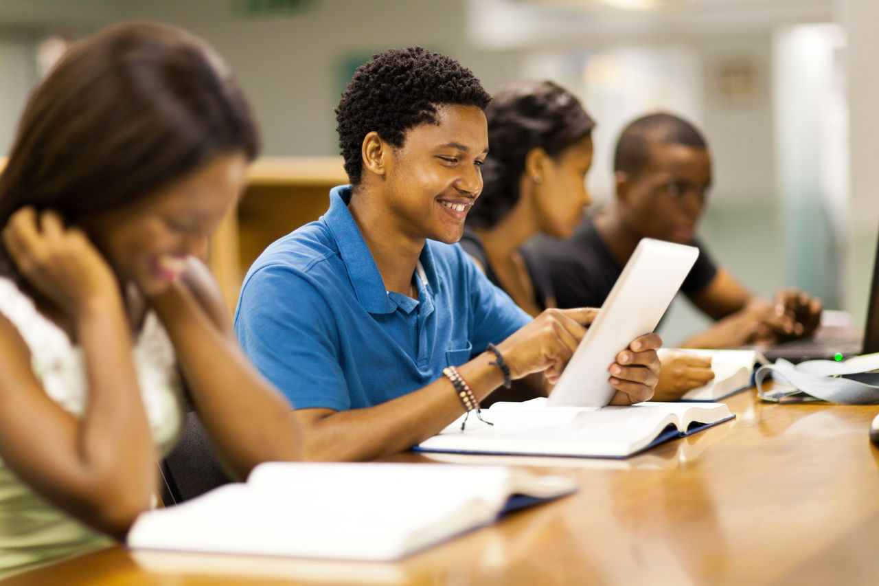 happy male african american college student using tablet computer
